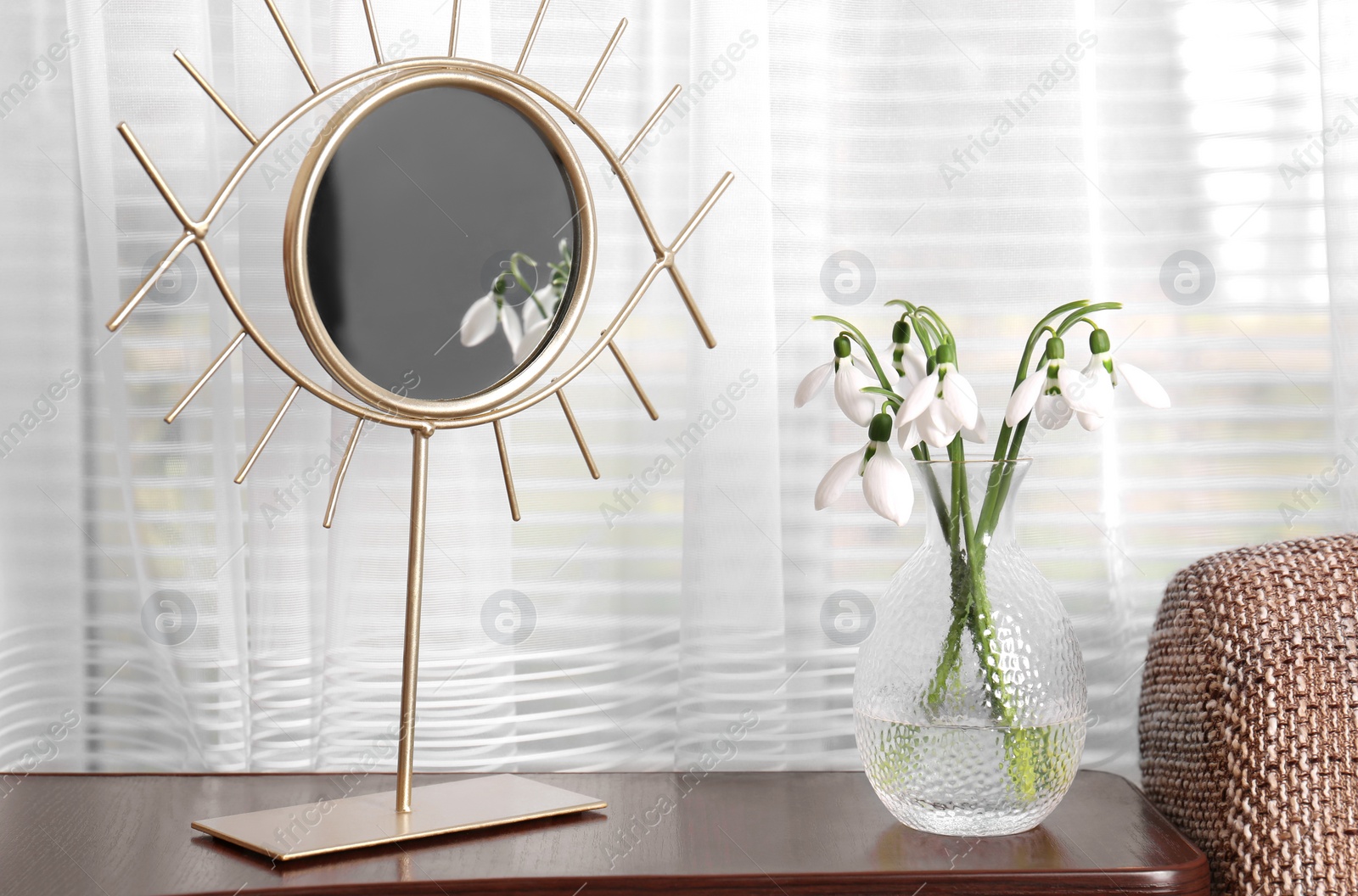 Photo of Beautiful snowdrops in vase and mirror on wooden table indoors