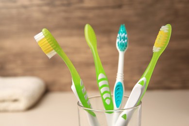 New toothbrushes in glass holder on blurred background, closeup