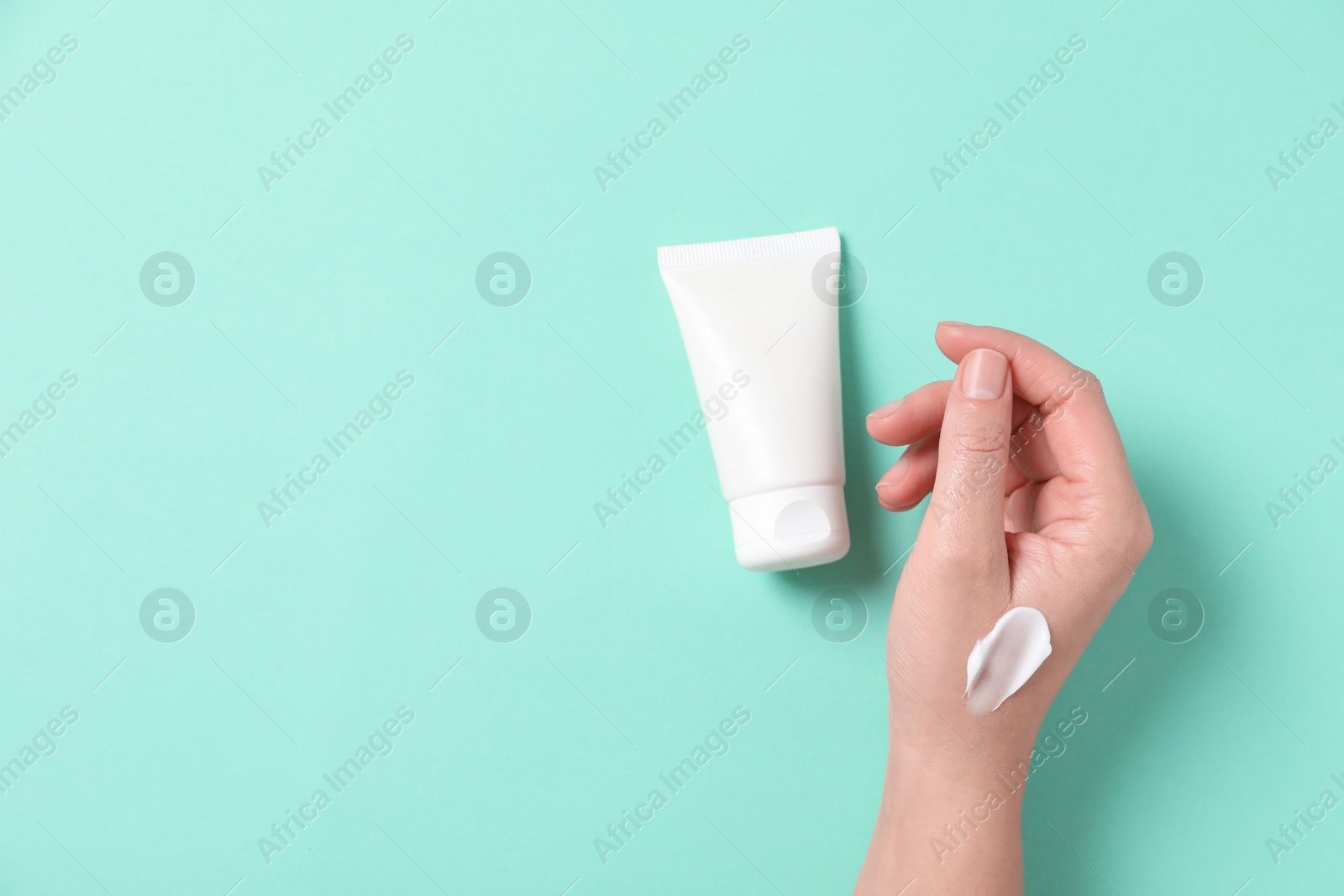 Photo of Woman with tube of hand cream on turquoise background, top view. Space for text