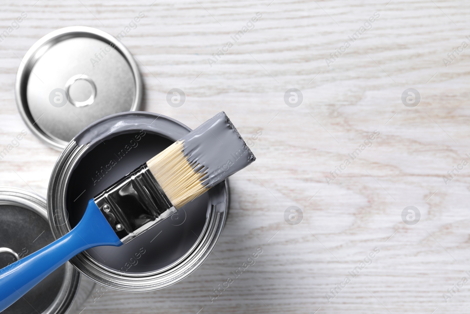 Photo of Cans of paints and brush on white wooden table, flat lay. Space for text