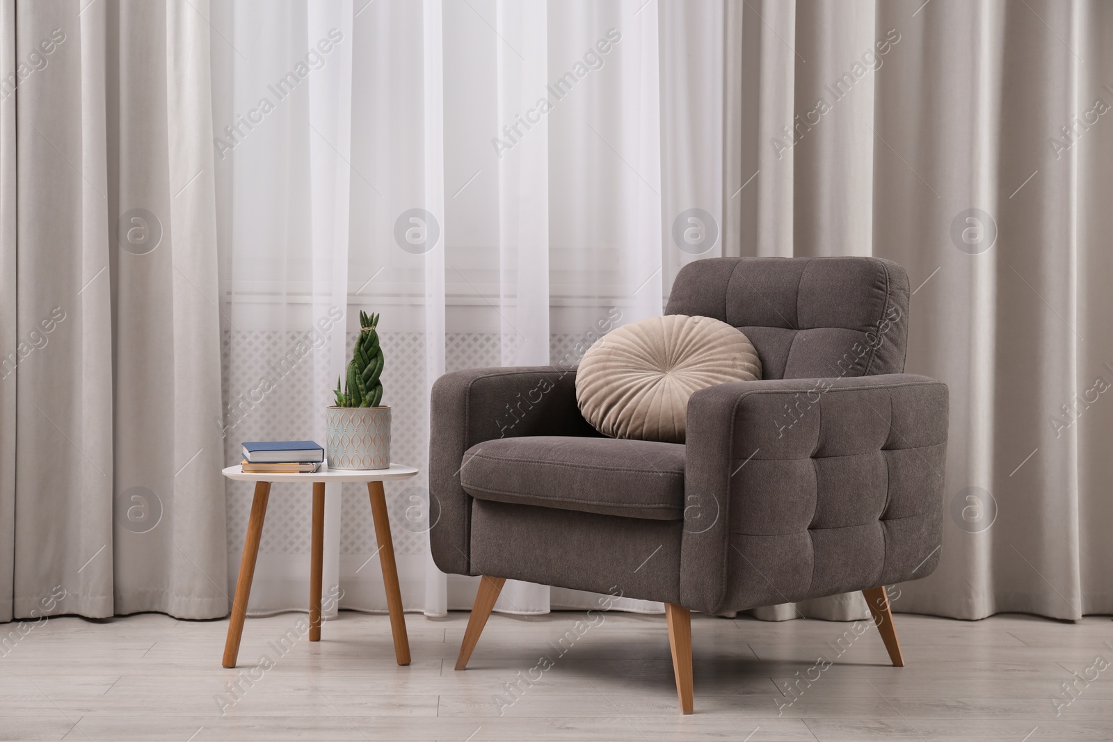 Photo of Comfortable armchair and plant near window in living room. Interior design