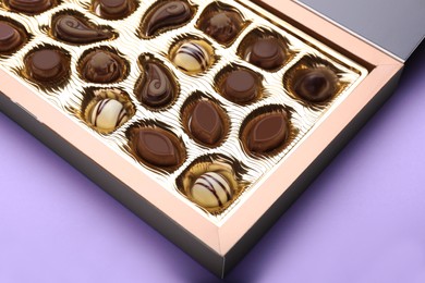 Box of delicious chocolate candies on violet background