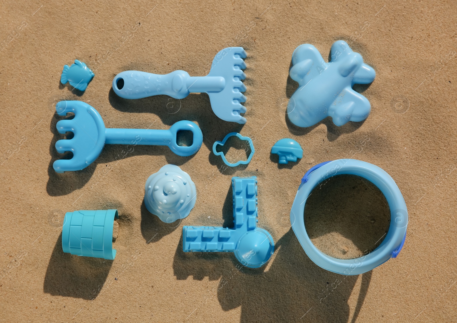 Photo of Set of plastic beach toys on sand, flat lay. Outdoor play