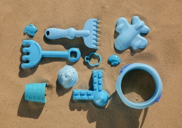 Set of plastic beach toys on sand, flat lay. Outdoor play