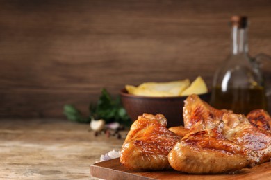 Photo of Delicious fried chicken wings on wooden table, space for text