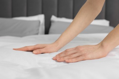 Young woman making bed in room, closeup