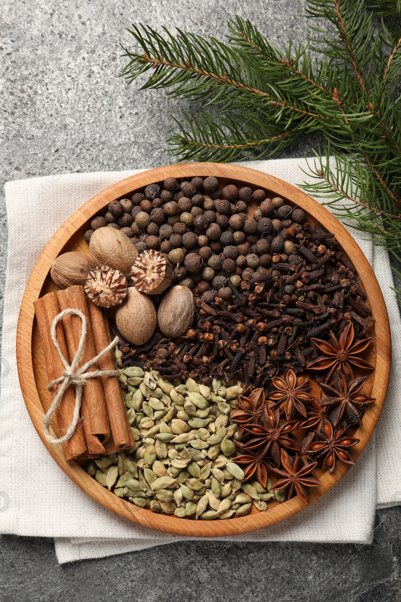 Photo of Different spices, nuts and fir branches on gray table, flat lay