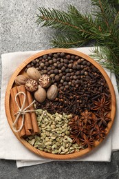 Photo of Different spices, nuts and fir branches on gray table, flat lay