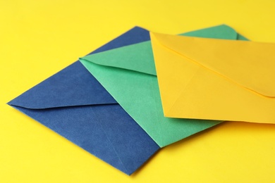 Colorful paper envelopes on yellow background, closeup