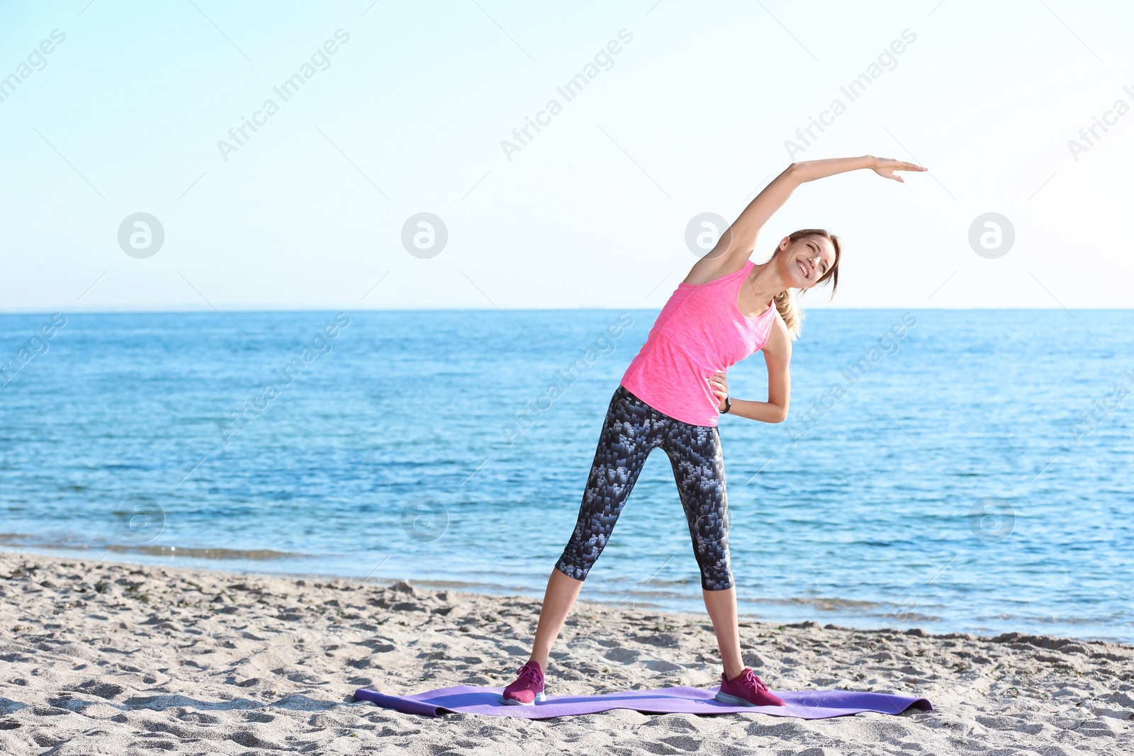 Photo of Young woman doing fitness exercises on beach in morning