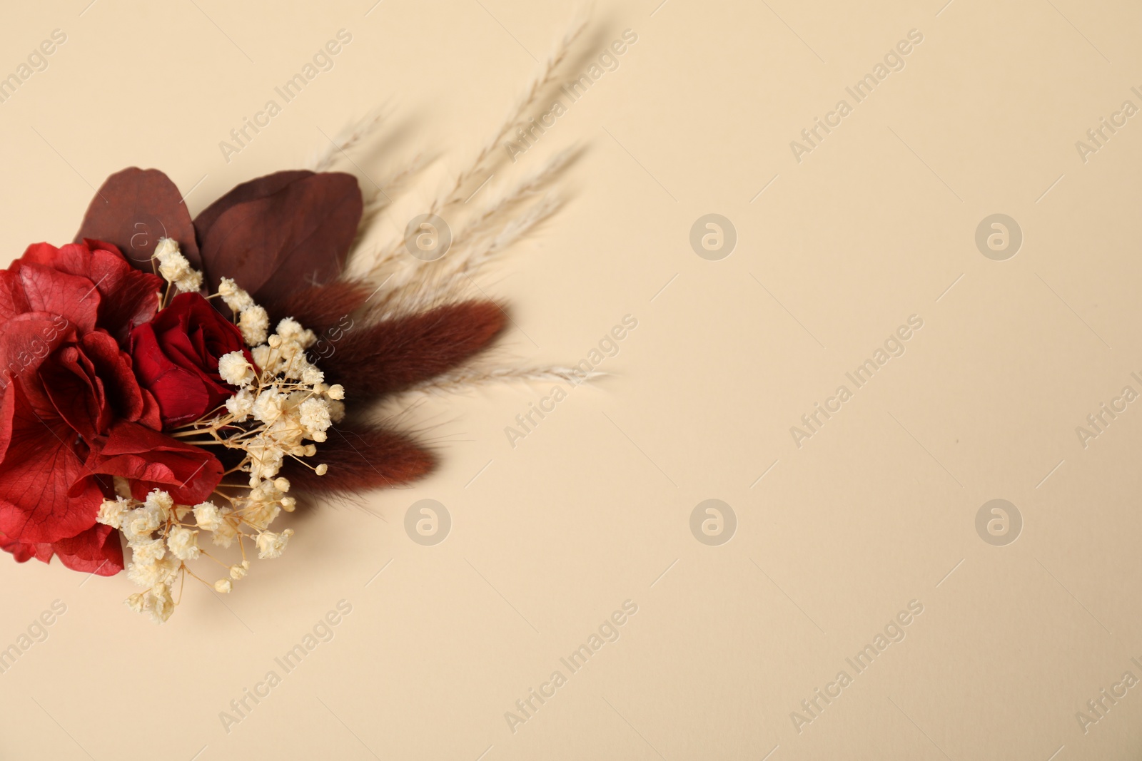 Photo of Stylish red boutonniere on beige background, top view. Space for text