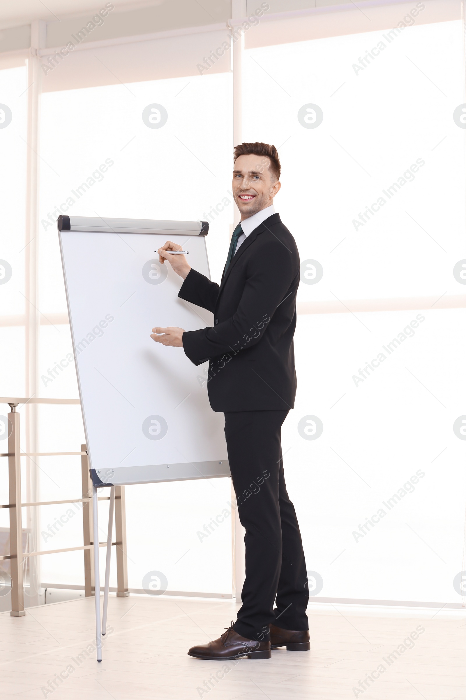 Photo of Young business trainer near flip chart, indoors