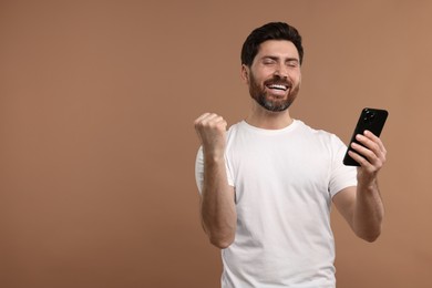 Photo of Happy man with smartphone on light brown background. Space for text