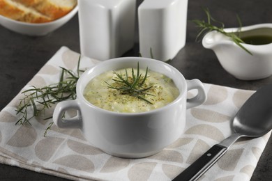 Photo of Delicious cream soup with tarragon, spices and potato in bowl served on dark table