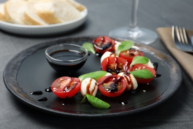 Photo of Fresh vegetable salad with mozzarella and balsamic vinegar on plate, closeup