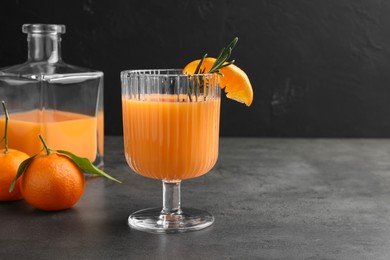 Photo of Delicious tangerine liqueur and fresh fruits on grey table, space for text