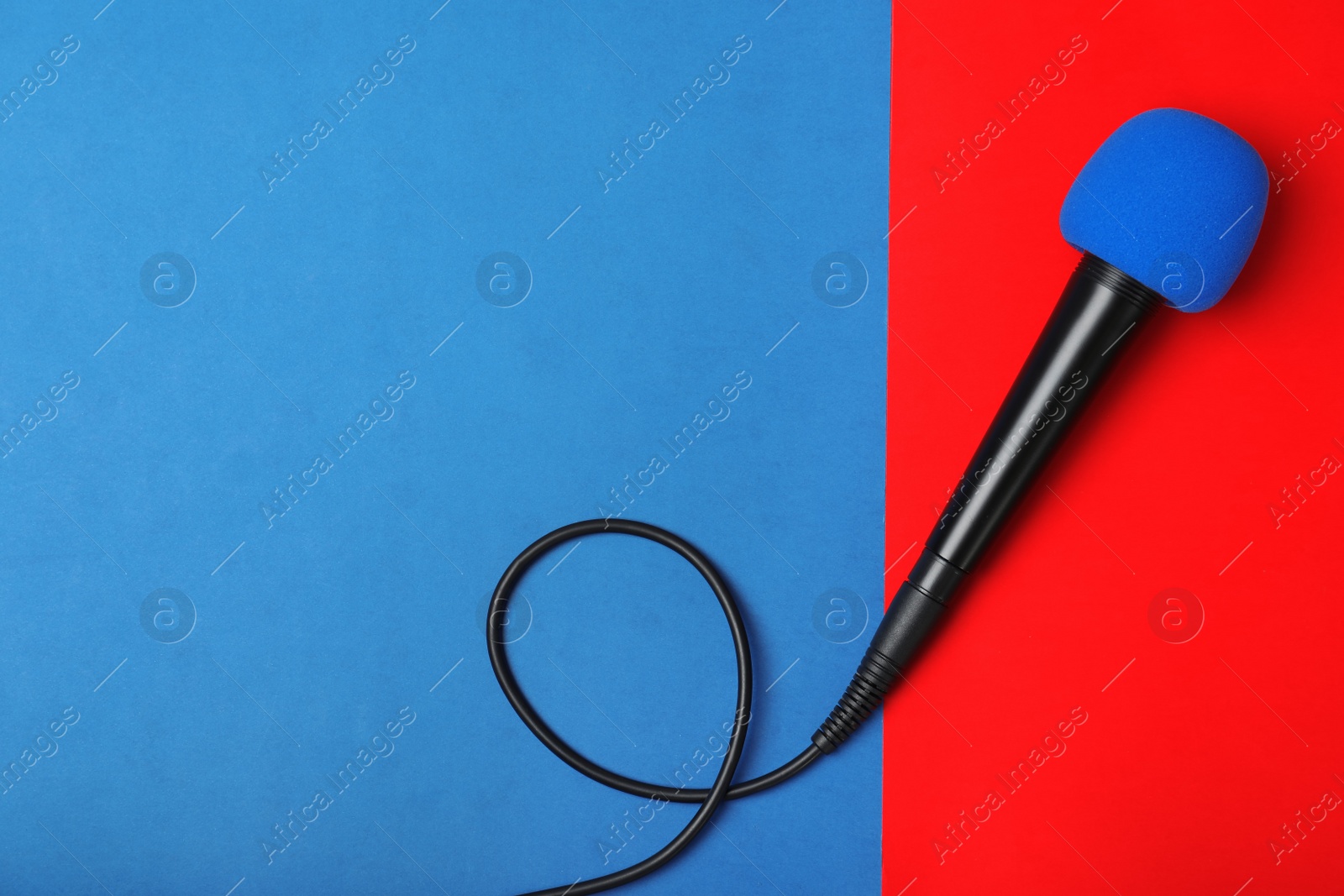 Photo of Modern microphone on color background, top view with space for text