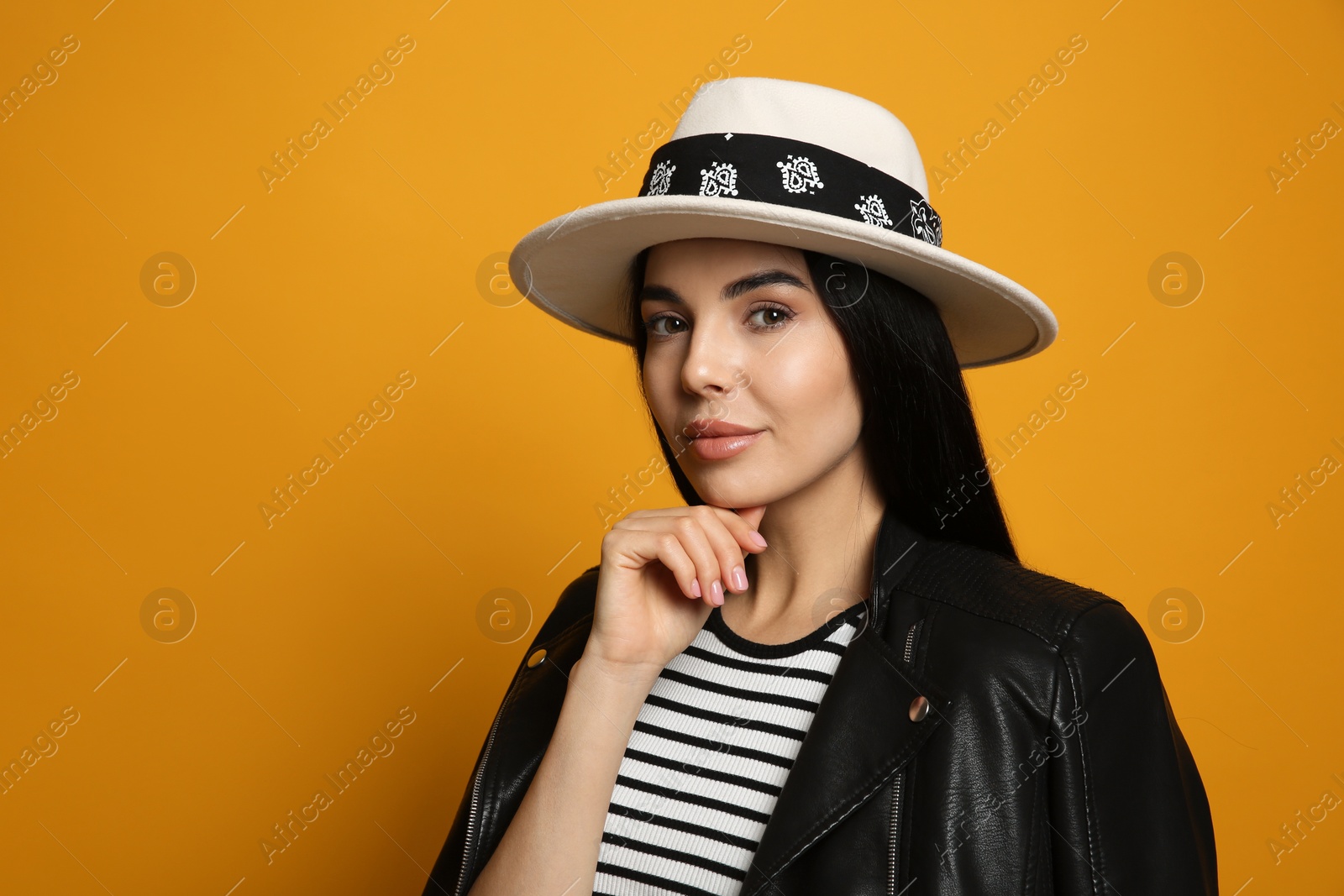 Photo of Fashionable young woman in stylish outfit with bandana on orange background