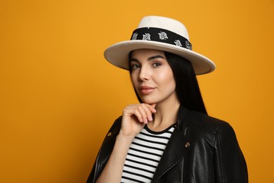 Photo of Fashionable young woman in stylish outfit with bandana on orange background