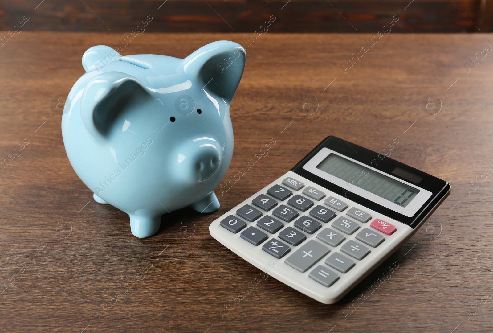 Photo of Calculator and piggy bank on wooden table