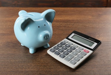 Calculator and piggy bank on wooden table