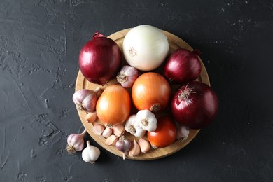 Fresh raw garlic and onions on black table, top view