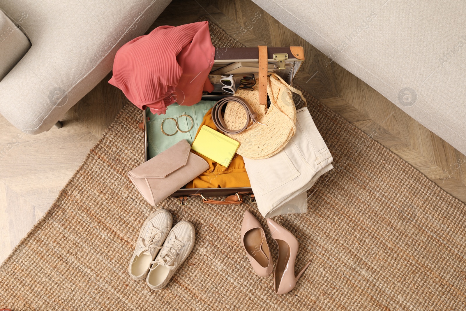 Photo of Open suitcase with different women clothes and accessories on carpet, top view