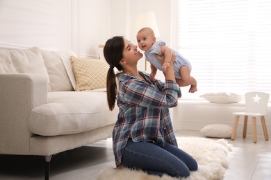 Photo of Happy young mother with her cute baby on floor at home