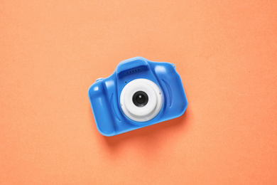 Toy camera on orange background, top view. Color of the year 2020 (Classic blue)