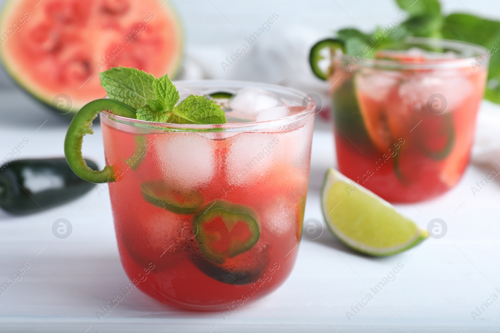 Photo of Spicy cocktail with jalapeno and mint on white table. Space for text