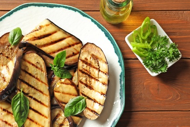 Plate with fried eggplant slices on wooden table, top view