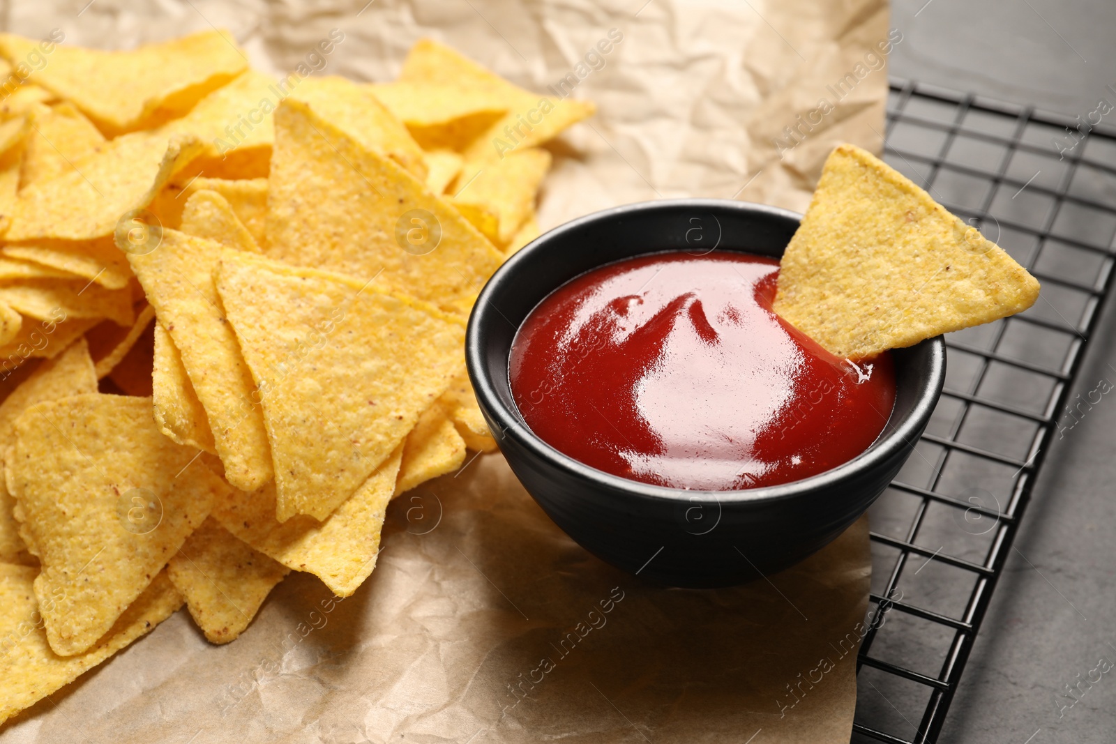 Photo of Tasty ketchup and tortilla chips on table, closeup