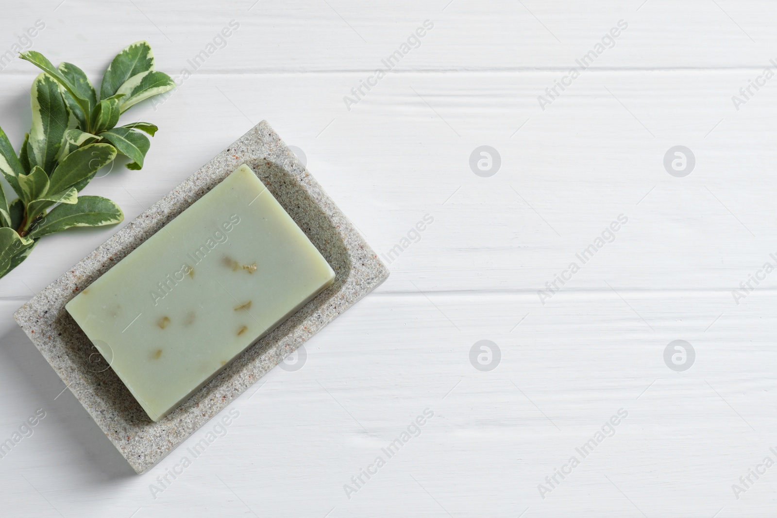 Photo of Soap bar and green leaf on white wooden table, top view. Space for text