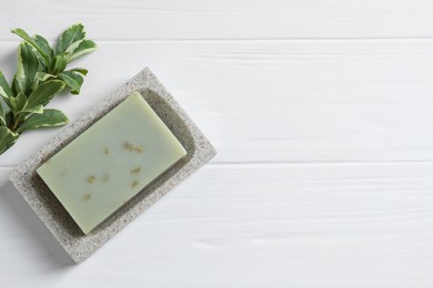 Soap bar and green leaf on white wooden table, top view. Space for text