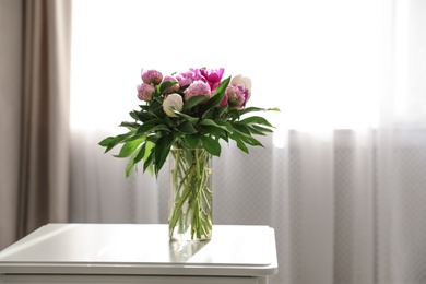 Photo of Vase with bouquet of beautiful peonies on table in room, space for text