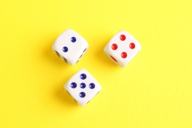 Photo of Three white game dices on yellow background, flat lay. Space for text
