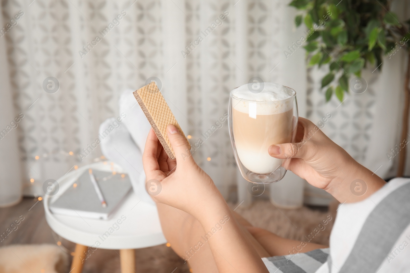 Photo of Woman having delicious wafer and coffee for breakfast indoors, closeup