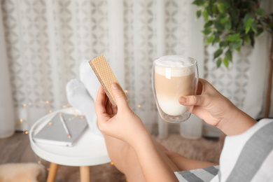 Photo of Woman having delicious wafer and coffee for breakfast indoors, closeup