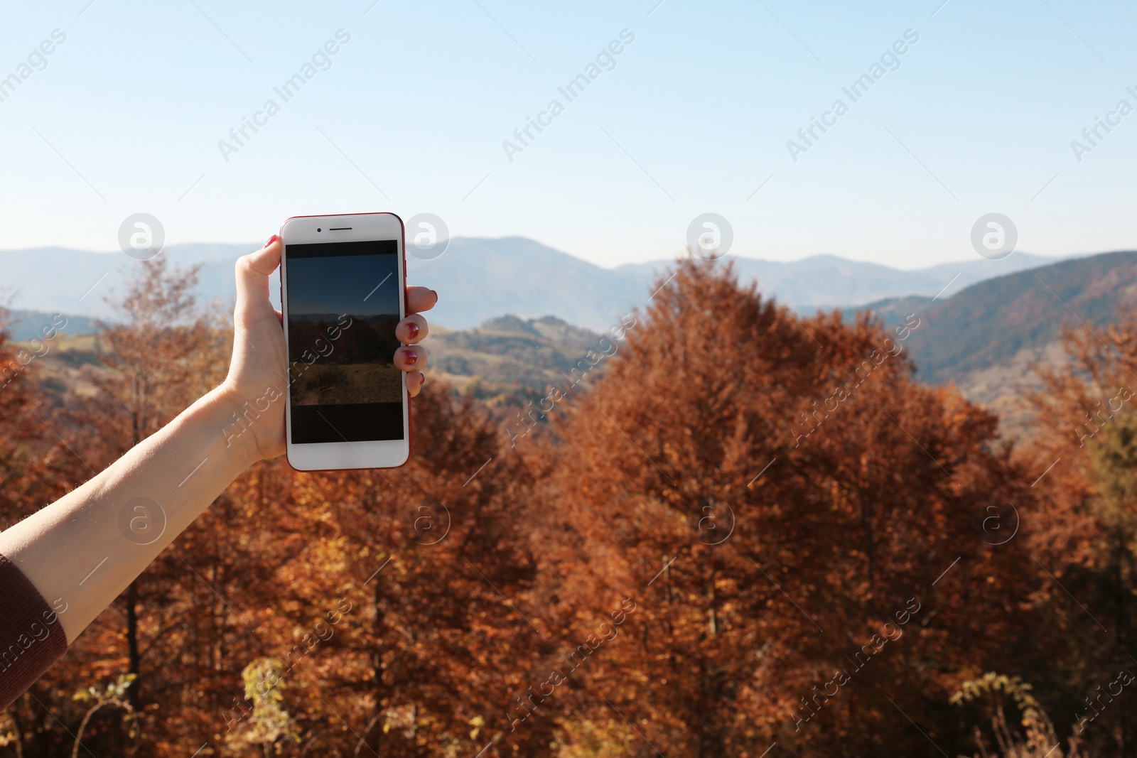 Photo of Woman taking photo of beautiful mountain landscape with smartphone