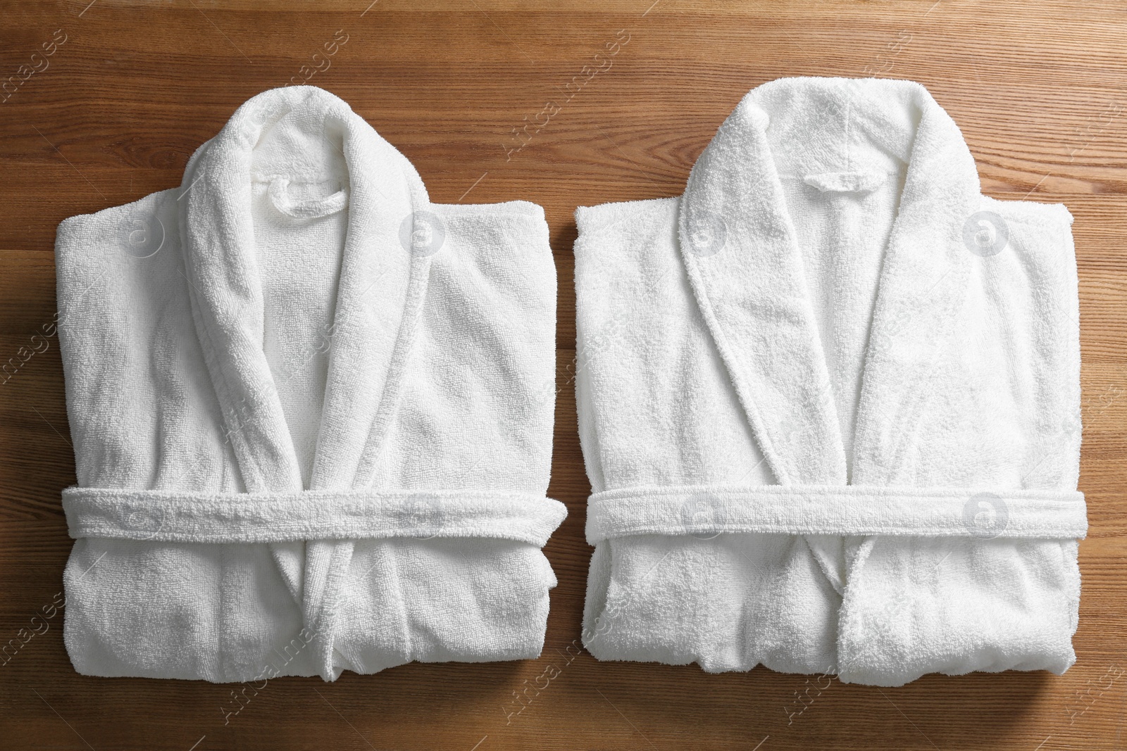 Photo of Clean folded bathrobes on wooden background, flat lay