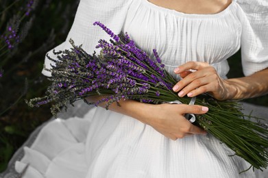 Woman with lavender bouquet sitting in field, closeup