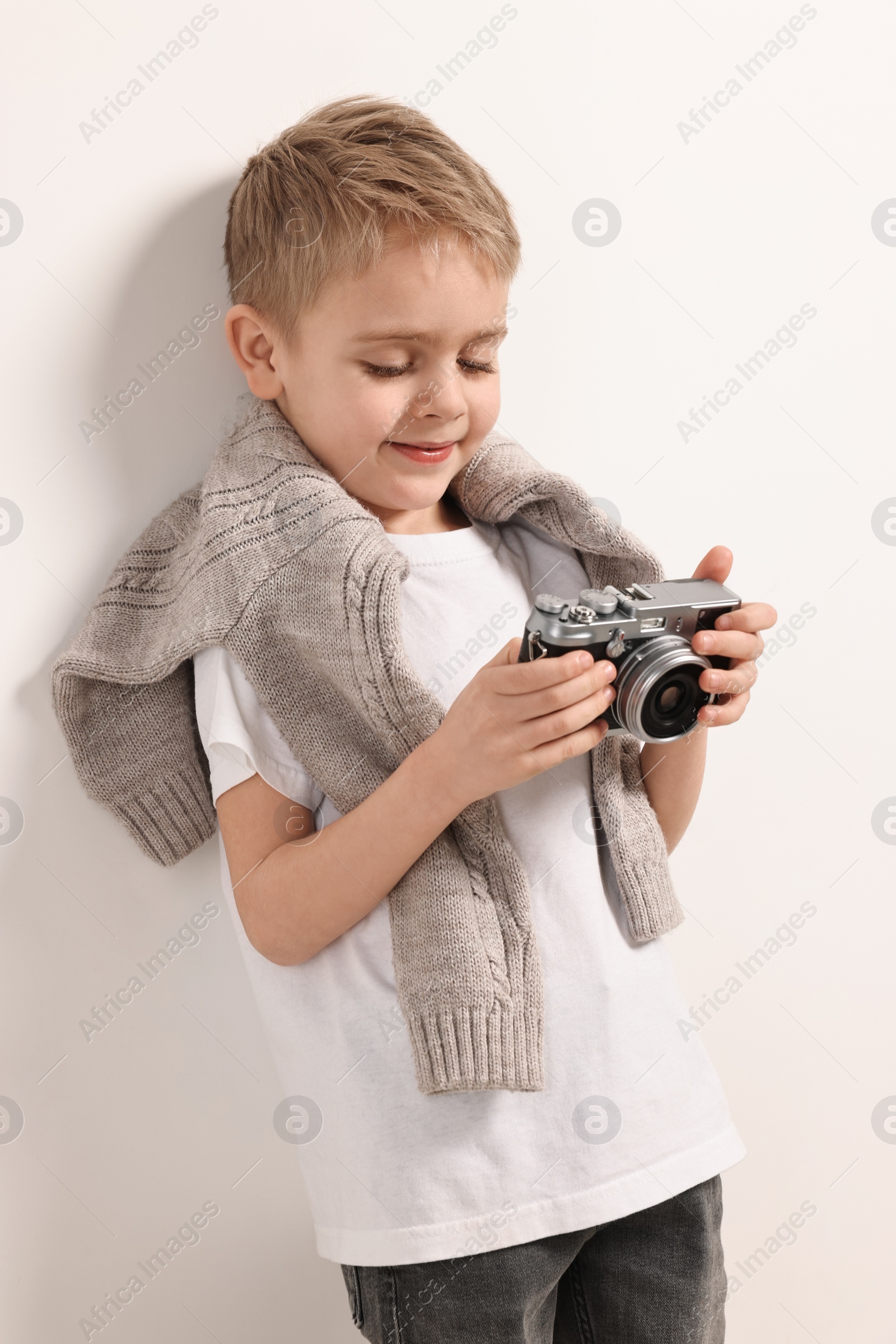 Photo of Fashion concept. Stylish boy with vintage camera on white background