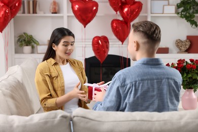 Photo of Woman receiving gift box from her boyfriend at home. Valentine's day celebration.
