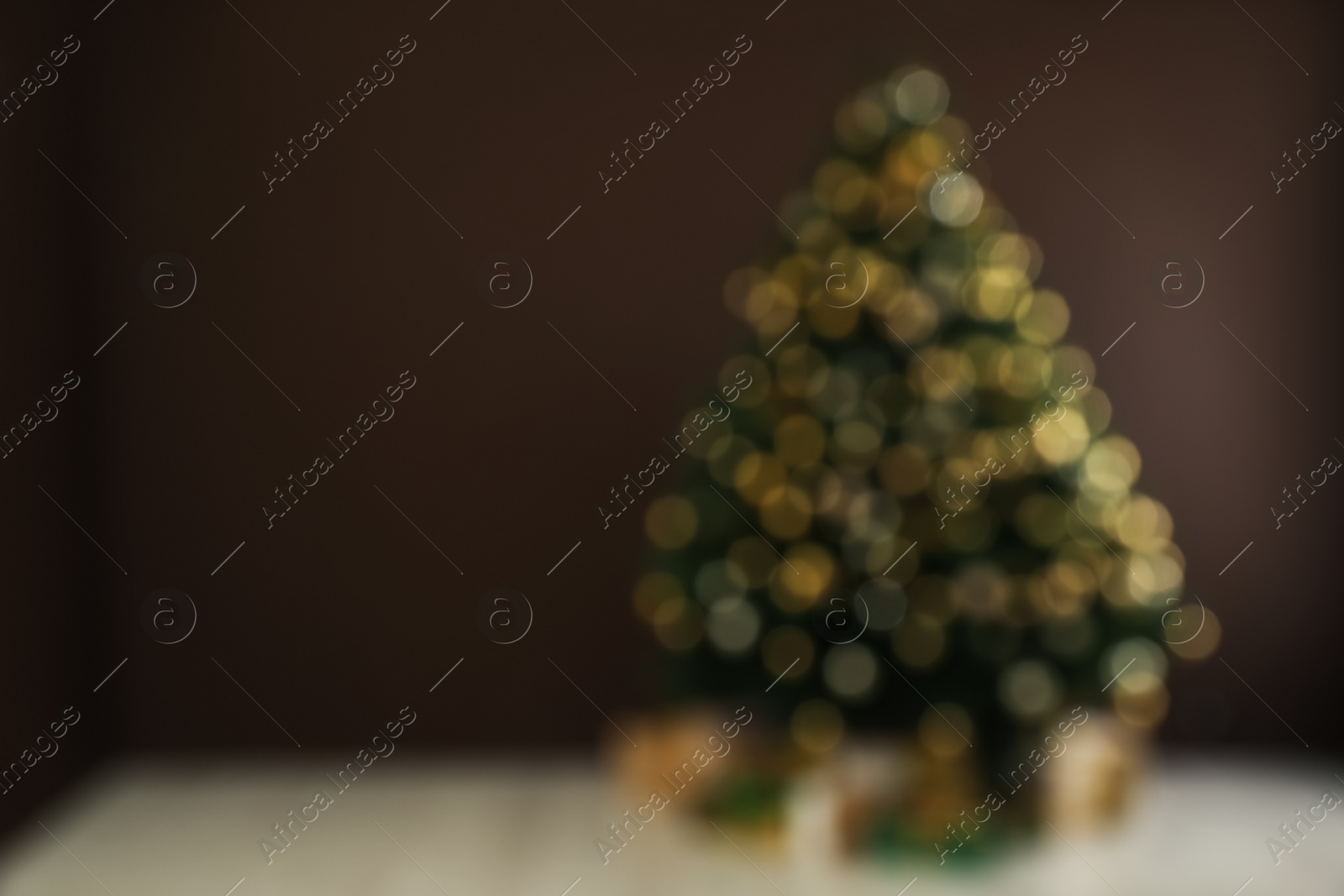 Photo of Blurred view of beautifully decorated Christmas tree near brown wall indoors, space for text