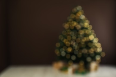 Photo of Blurred view of beautifully decorated Christmas tree near brown wall indoors, space for text