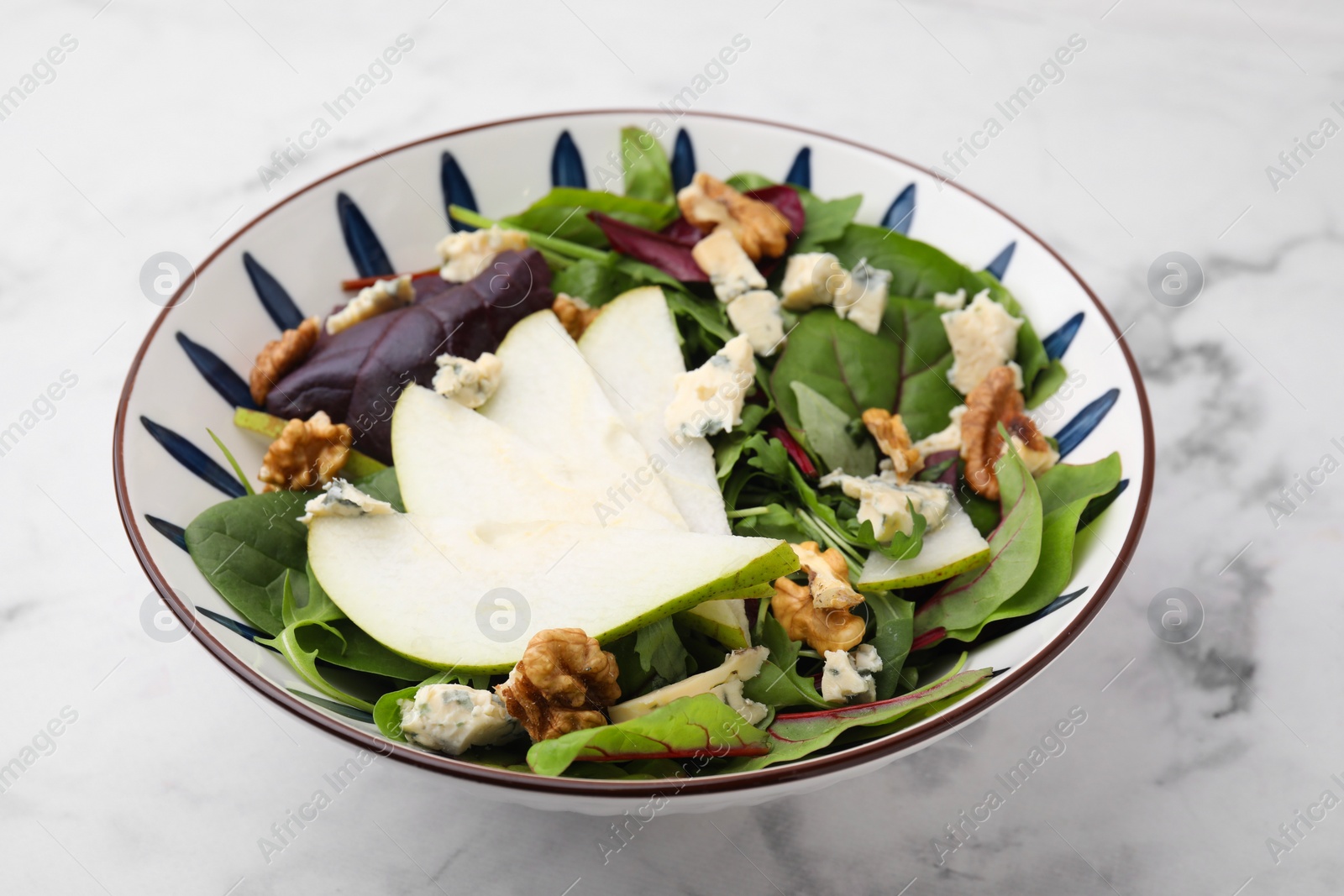 Photo of Delicious pear salad in bowl on white marble table, closeup