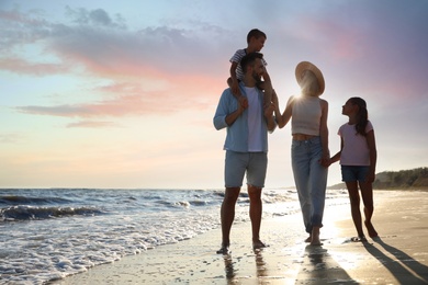 Happy family walking on sandy beach near sea