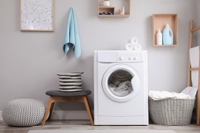 Photo of Laundry room interior with modern washing machine near light wall