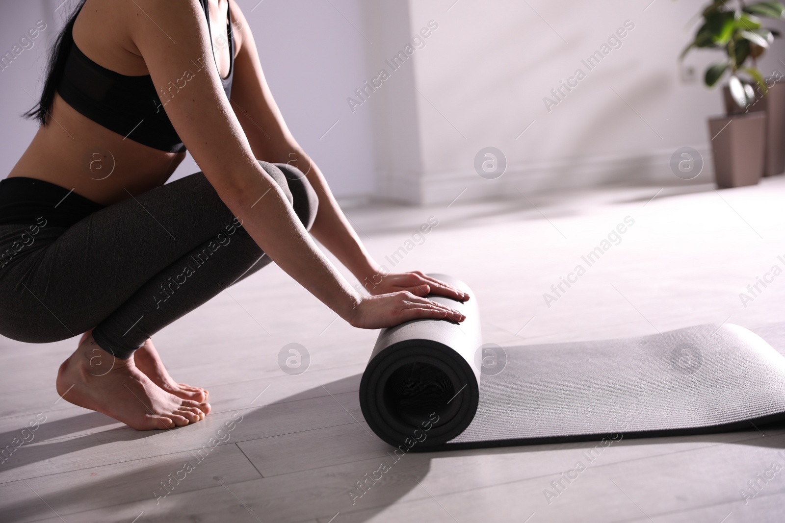 Photo of Woman rolling yoga mat in studio, closeup