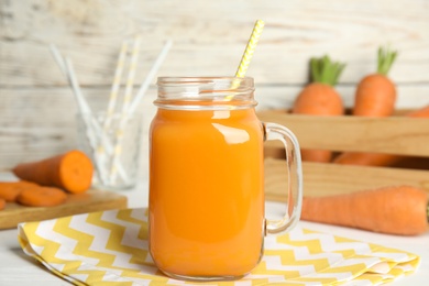 Freshly made carrot juice in mason jar on white table